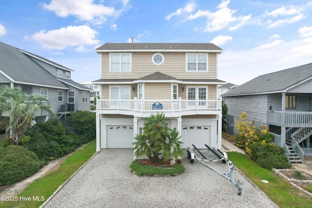 view of front of home featuring a garage, cooling unit, and a balcony