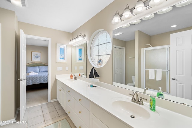 bathroom with toilet, vanity, an enclosed shower, and tile patterned flooring