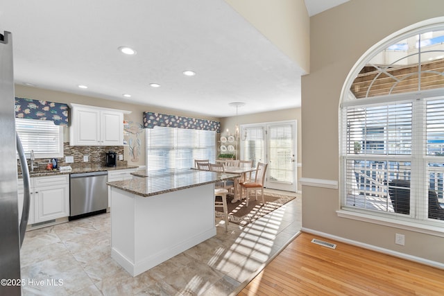 kitchen featuring dishwasher, decorative light fixtures, white cabinetry, light stone countertops, and decorative backsplash