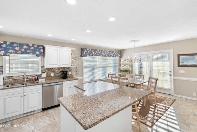 kitchen with dishwasher, hanging light fixtures, sink, tasteful backsplash, and a center island