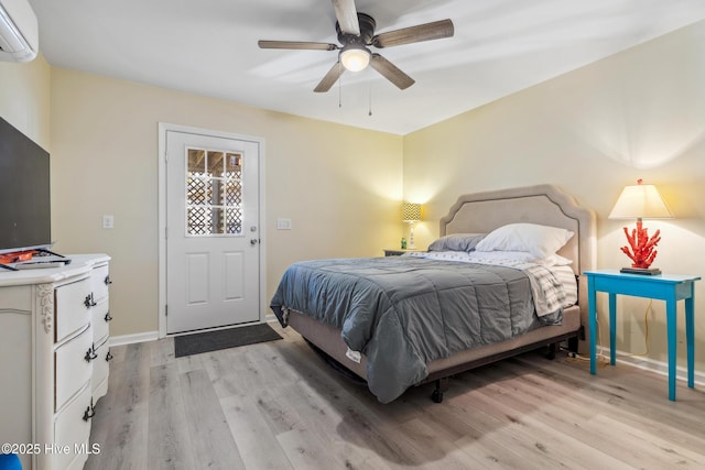 bedroom featuring ceiling fan, a wall mounted air conditioner, and light hardwood / wood-style floors