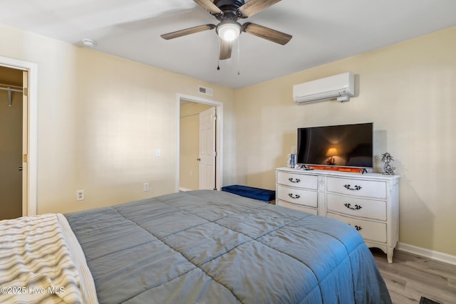 bedroom featuring ceiling fan, light hardwood / wood-style floors, and a wall mounted AC