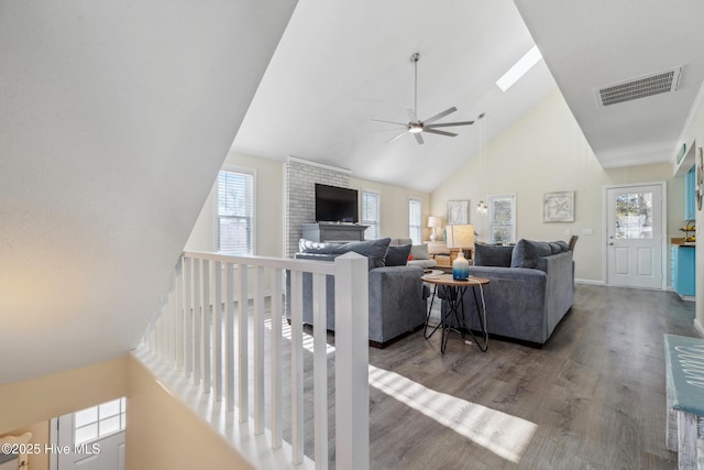 living room featuring ceiling fan, high vaulted ceiling, a skylight, and hardwood / wood-style floors