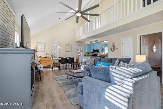 living room featuring ceiling fan, high vaulted ceiling, ornamental molding, and light hardwood / wood-style floors