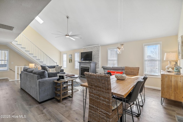 interior space featuring lofted ceiling, dark hardwood / wood-style flooring, a wealth of natural light, and a large fireplace