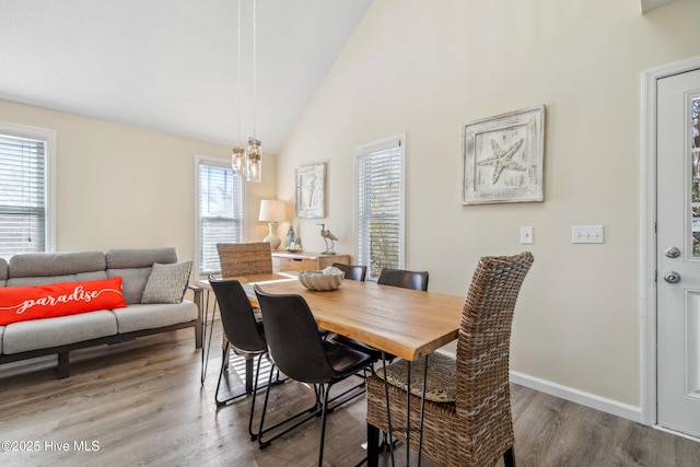 dining space featuring an inviting chandelier, hardwood / wood-style floors, and high vaulted ceiling