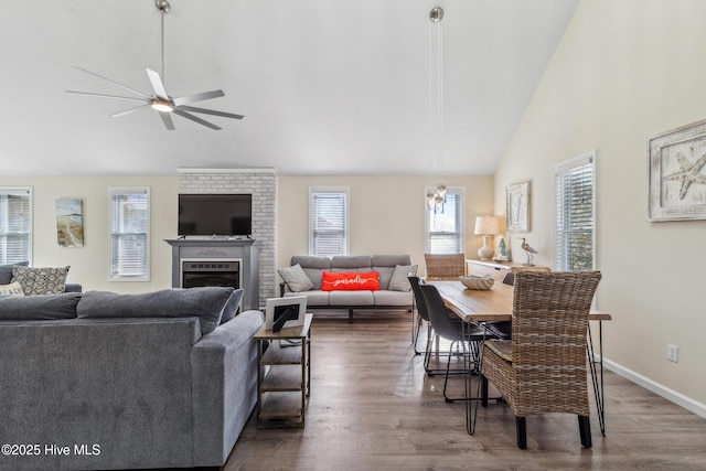 living room with ceiling fan, a fireplace, dark hardwood / wood-style flooring, and high vaulted ceiling