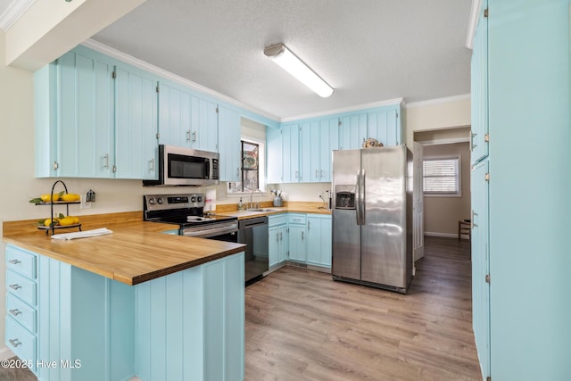 kitchen with sink, ornamental molding, appliances with stainless steel finishes, kitchen peninsula, and light hardwood / wood-style floors