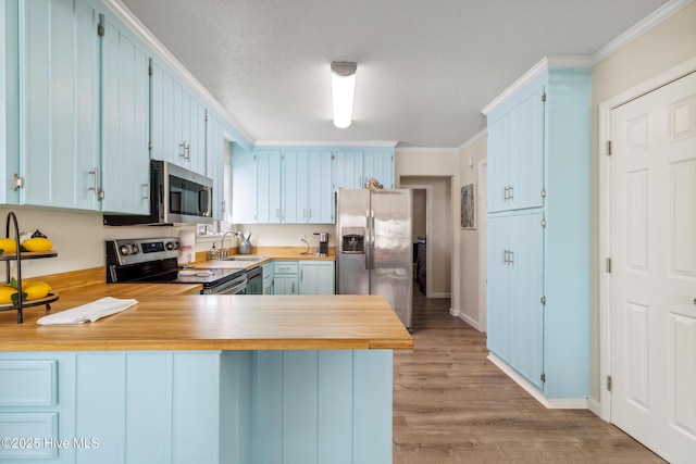 kitchen featuring blue cabinetry, crown molding, kitchen peninsula, stainless steel appliances, and light hardwood / wood-style floors