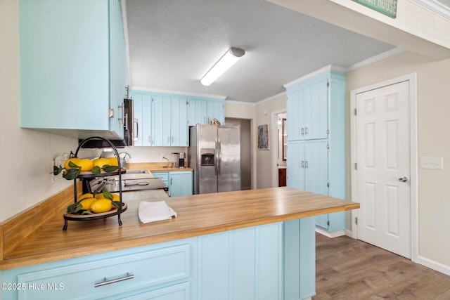 kitchen featuring blue cabinetry, ornamental molding, stainless steel fridge, and kitchen peninsula