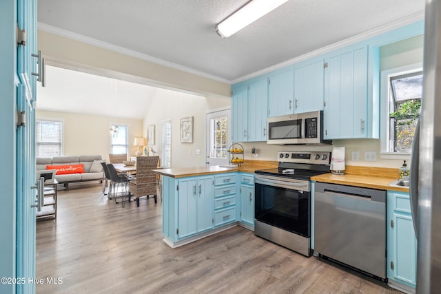 kitchen with lofted ceiling, kitchen peninsula, stainless steel appliances, blue cabinetry, and light hardwood / wood-style flooring