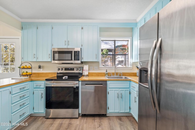 kitchen featuring stainless steel appliances, sink, blue cabinetry, and light hardwood / wood-style flooring