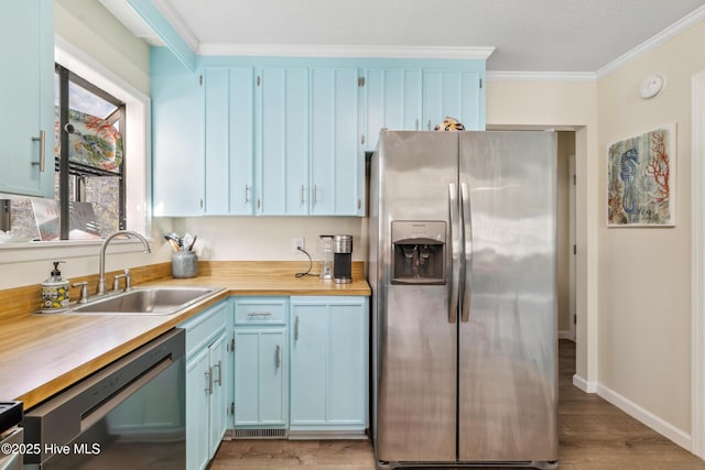 kitchen featuring sink, crown molding, stainless steel fridge, black dishwasher, and light wood-type flooring