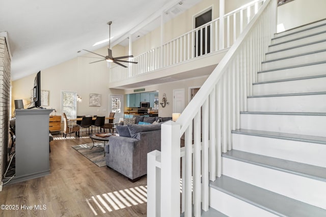 stairway featuring high vaulted ceiling, hardwood / wood-style floors, and ceiling fan