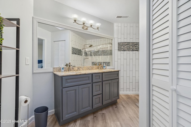 bathroom with hardwood / wood-style flooring, vanity, and tiled shower