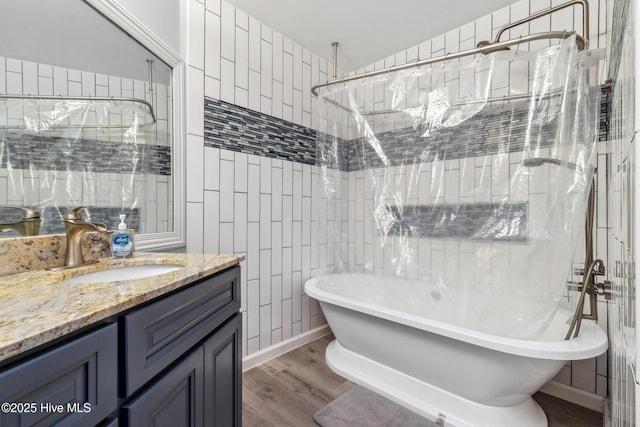 bathroom featuring hardwood / wood-style flooring, plus walk in shower, tile walls, and vanity