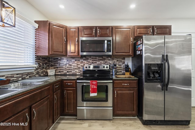 kitchen featuring backsplash, light wood-type flooring, dark brown cabinetry, and stainless steel appliances