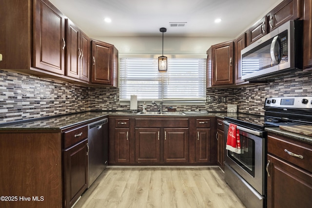 kitchen featuring appliances with stainless steel finishes, sink, decorative light fixtures, light wood-type flooring, and decorative backsplash