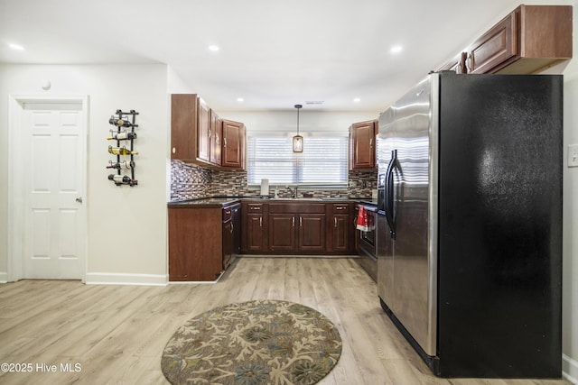 kitchen with light hardwood / wood-style flooring, appliances with stainless steel finishes, decorative light fixtures, sink, and backsplash