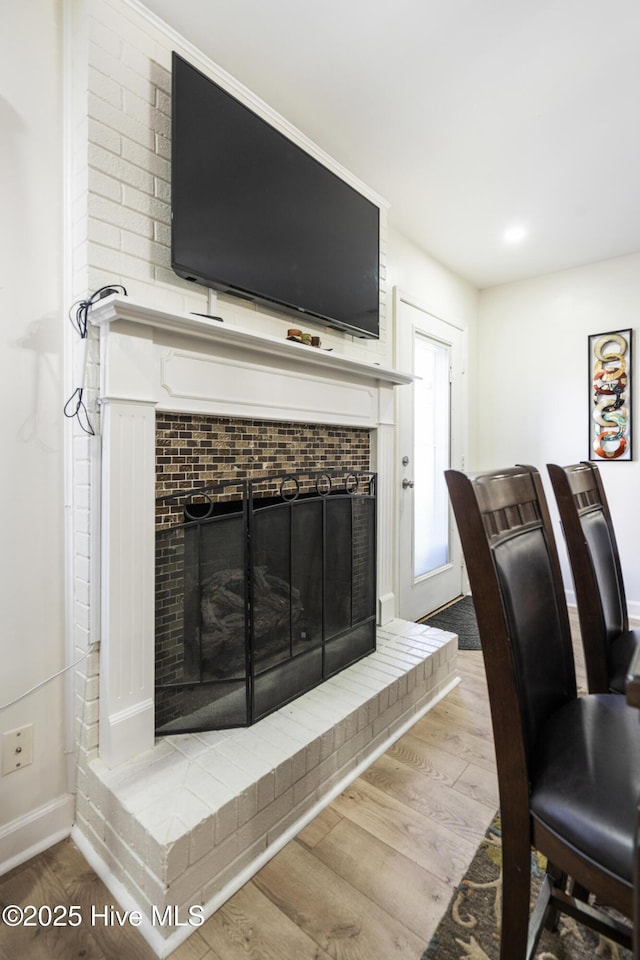 home office with a brick fireplace and light hardwood / wood-style floors