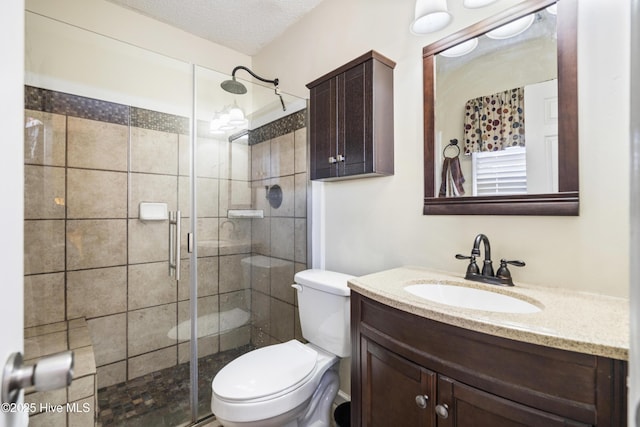 bathroom with toilet, a shower with door, a textured ceiling, and vanity