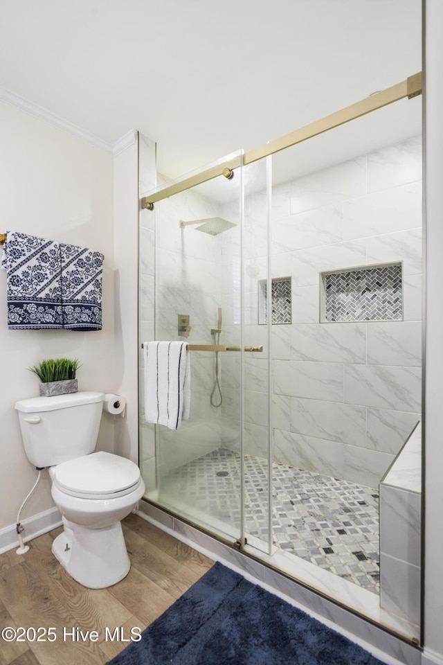 bathroom featuring toilet, crown molding, an enclosed shower, and wood-type flooring