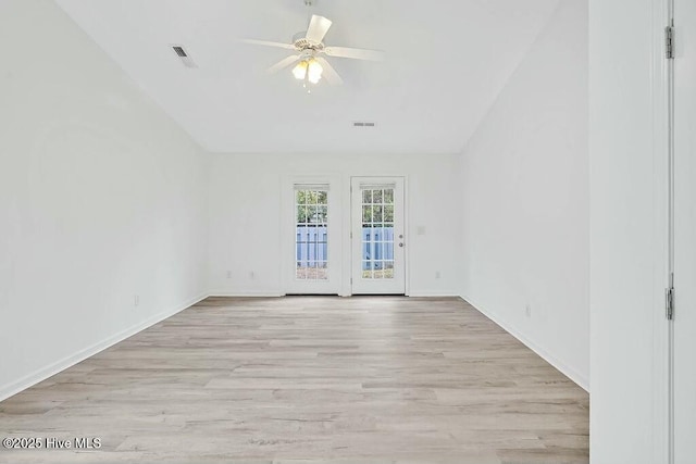 unfurnished room with light wood finished floors, baseboards, visible vents, and vaulted ceiling