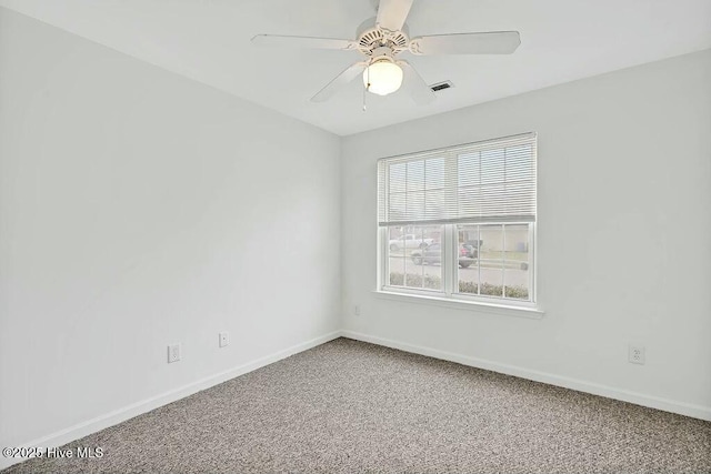 carpeted spare room with visible vents, baseboards, and ceiling fan