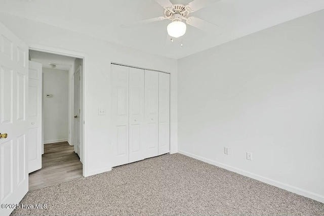 unfurnished bedroom with ceiling fan, a closet, baseboards, and carpet flooring