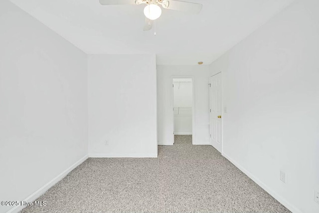 unfurnished bedroom with baseboards, ceiling fan, carpet, a walk in closet, and a closet