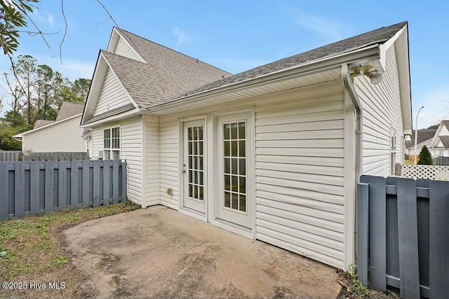 rear view of property with a shingled roof, fence, and a patio