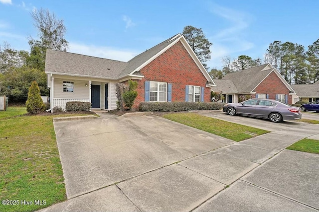 view of front of house with a porch, a front yard, concrete driveway, and brick siding