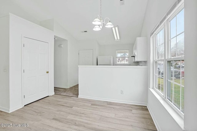 spare room with a notable chandelier, visible vents, light wood-style floors, vaulted ceiling, and baseboards