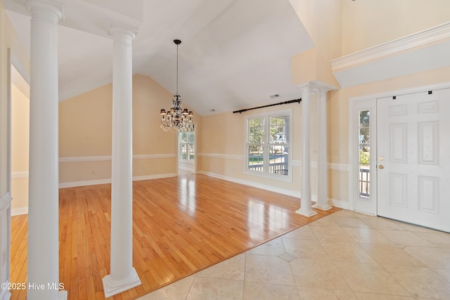 foyer entrance with high vaulted ceiling, decorative columns, and light tile patterned floors