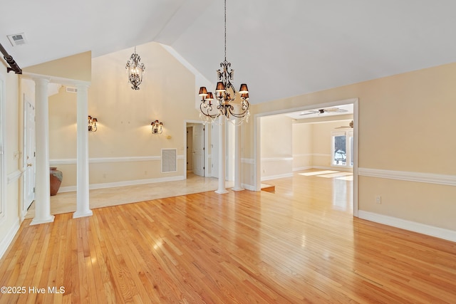 interior space with ornate columns, lofted ceiling, hardwood / wood-style flooring, and ceiling fan with notable chandelier