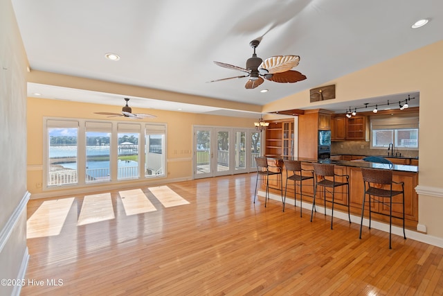 kitchen featuring a breakfast bar, sink, a water view, light wood-type flooring, and kitchen peninsula