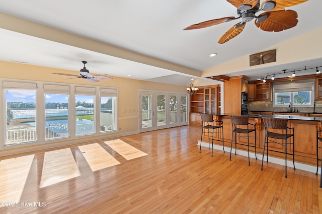 living room featuring a water view, ceiling fan with notable chandelier, and light hardwood / wood-style floors