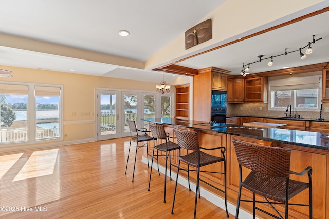 kitchen featuring dark stone countertops, hanging light fixtures, black appliances, and a kitchen bar