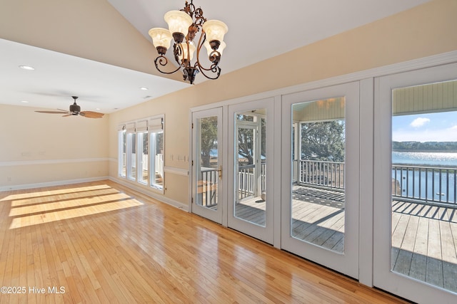 doorway with ceiling fan with notable chandelier, light hardwood / wood-style floors, and a water view