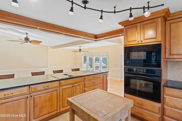 kitchen with backsplash, ceiling fan, a kitchen island, and black appliances