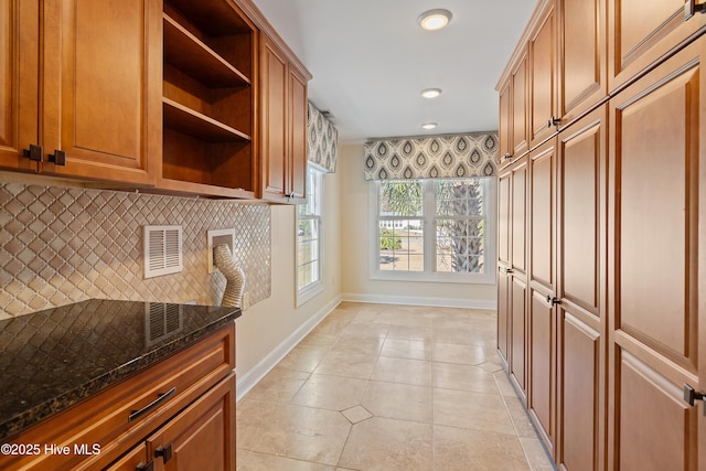 kitchen with dark stone countertops, decorative backsplash, and light tile patterned floors