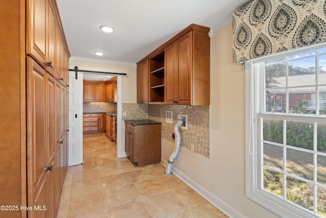 kitchen with tasteful backsplash, dark stone counters, a barn door, and plenty of natural light