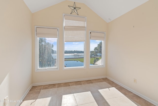 spare room with a water view, light tile patterned floors, and lofted ceiling