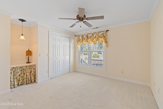 unfurnished bedroom featuring crown molding, carpet, ceiling fan, and a closet