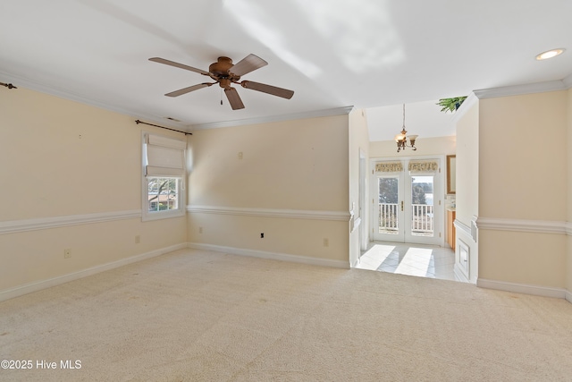 carpeted empty room with ornamental molding, ceiling fan with notable chandelier, and french doors