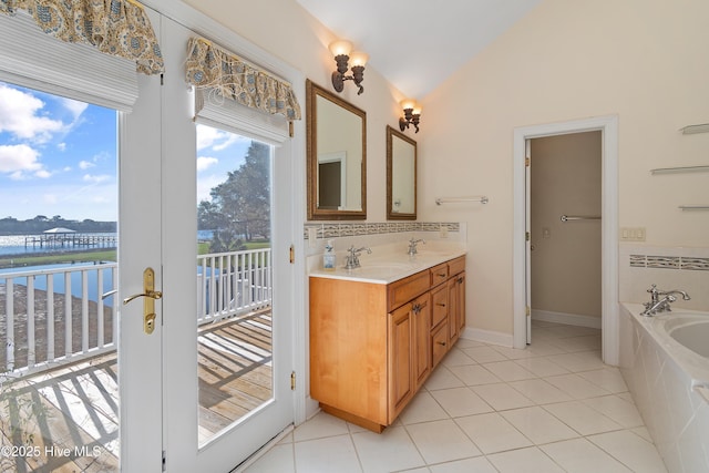 bathroom featuring vaulted ceiling, vanity, tiled tub, a water view, and tile patterned floors