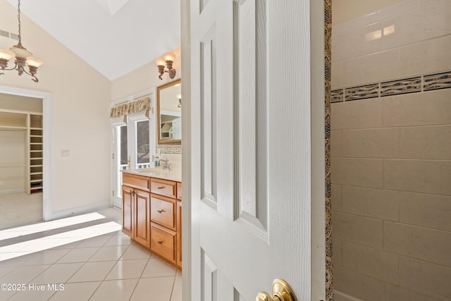 bathroom with tile patterned flooring, vanity, lofted ceiling, and a chandelier