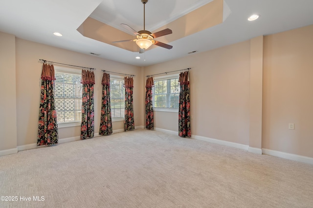 carpeted spare room featuring ceiling fan and a tray ceiling