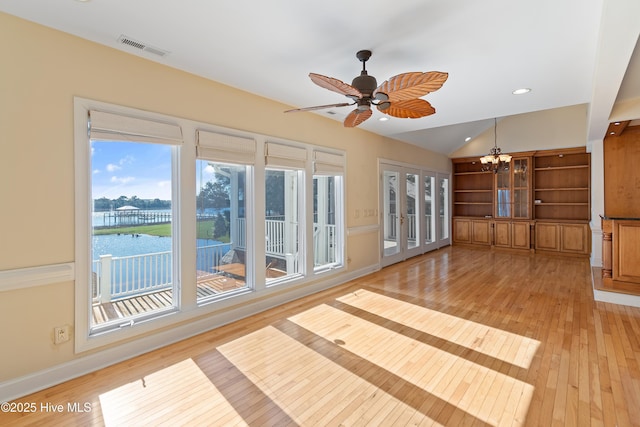 interior space with vaulted ceiling, ceiling fan with notable chandelier, light hardwood / wood-style floors, a water view, and french doors