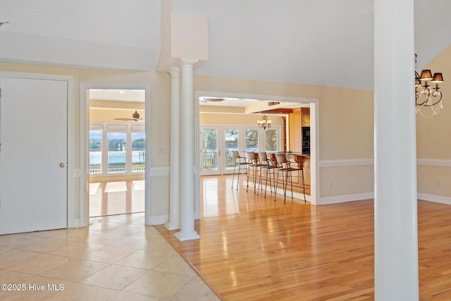 interior space featuring ceiling fan with notable chandelier, light wood-type flooring, and ornate columns